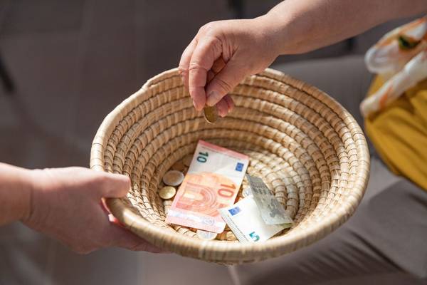 Ein geflochtenes Körbchen wird herumgereicht, um Geld einzusammeln. Ein paar Scheine und Münzen befinden sich bereits darin.